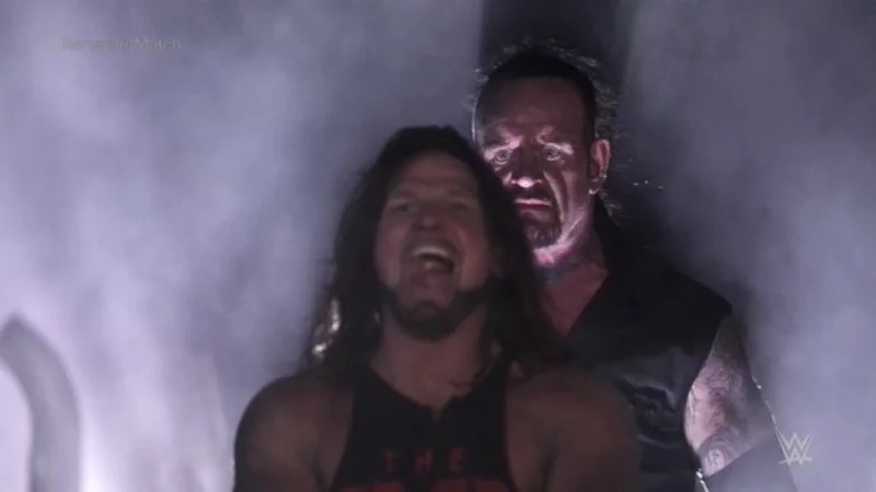 AJ Styles and Undertaker meme template: the Undertaker looming silently behind an oblivious, smiling AJ Styles