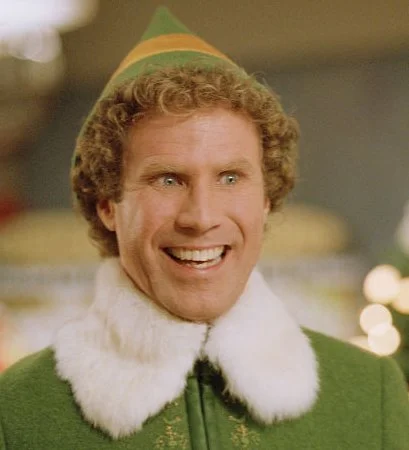 Buddy the Elf smiling excitedly in his green costume