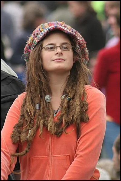 Young woman with dreadlocks and glasses looking slightly smug