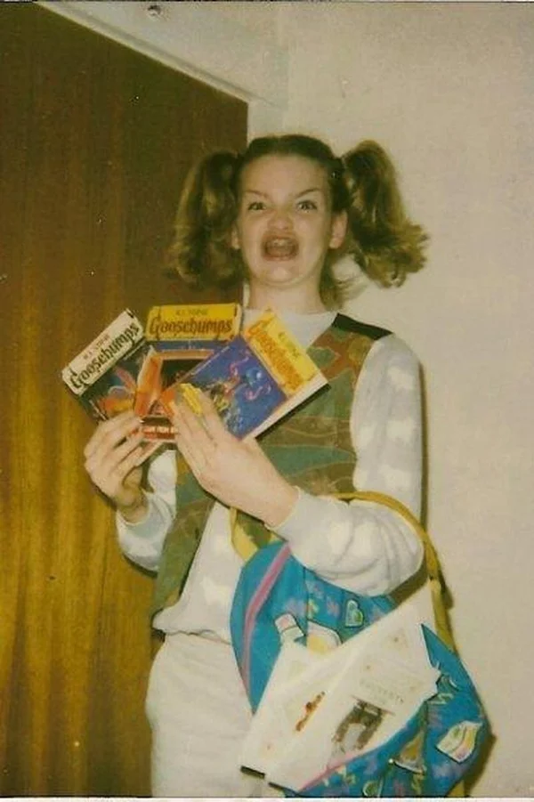 Ermahgerd meme template: a young girl with pigtails holding Goosebumps books with a wide-eyed open-mouthed grin