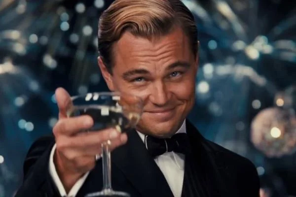Leonardo DiCaprio Cheers meme template: Jay Gatsby raising a coupe glass with a knowing smirk in The Great Gatsby