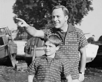 Father and son in matching shirts pointing at something in the distance