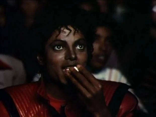 Michael Jackson in red Thriller jacket eating popcorn in a theater